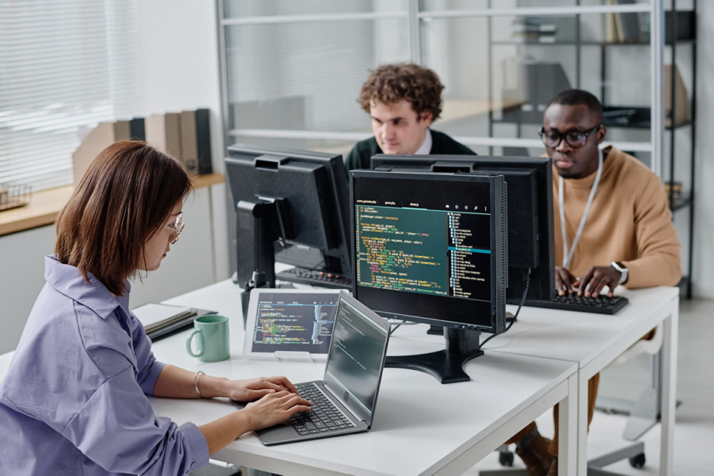 This image shows a team of software developers collaborating in a modern office while working on code. It highlights remote AI development, teamwork, and software engineering in a professional workspace.