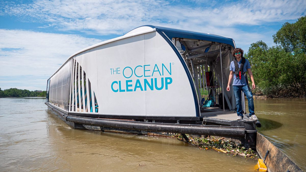 This image illustrates an ocean-cleanup vessel collecting plastic waste and debris from a river, highlighting innovative technology and efforts to reduce water pollution and protect marine ecosystems.