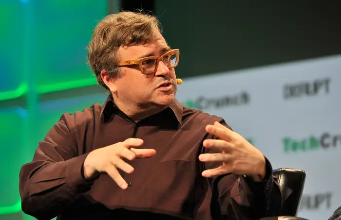 This image illustrates Reid Hoffman, co-founder of LinkedIn, during a speaking event. It can be used to visually support an article about his net worth, entrepreneurial career, LinkedIn success, and technology investments.