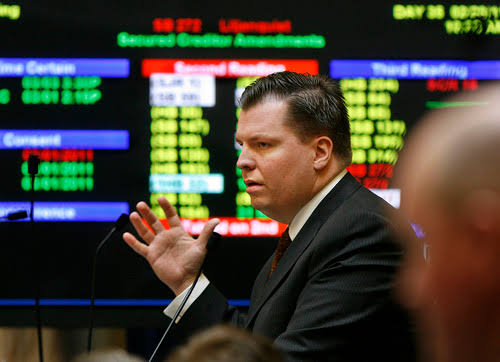 This image shows a professional trader or financial market specialist working in a busy trading environment, with market data and stock information displayed on screens in the background. It can be used for content about stock trading, financial markets, investment, traders, securities, Wall Street, or market analysis.