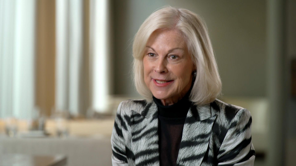 The image portrays a mature professional woman in an interview or formal discussion setting. It is suitable for editorial, corporate, leadership, or documentary content.