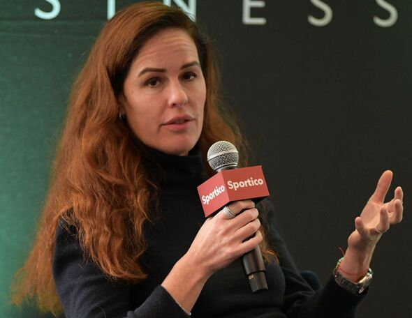 The image depicts a woman speaking at a sports-related conference, panel discussion, or professional event. It highlights public speaking, sports journalism, and professional communication.
